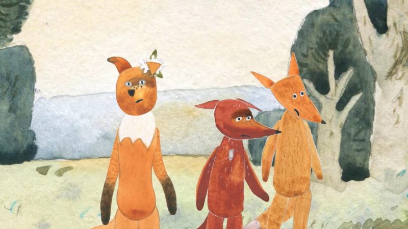 Ilustração em aquarela mostra três raposas antropomorfizadas lado a lado em um campo. A da esquerda tem expressão surpresa com uma flor presa na orelha, a do meio parece séria e a da direita sorri levemente, todas diante de árvores ao fundo.