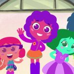 Ilustração colorida mostra cinco personagens infantis animados: um menino azul de uniforme sorridente, uma garota rosa com óculos de proteção, uma menina roxa de cabelo cacheado acenando, outra menina verde de vestido lilás sorrindo e um garoto verde de cabelo azul ao fundo. Ao lado, há uma garrafa rosa com coroa dourada.