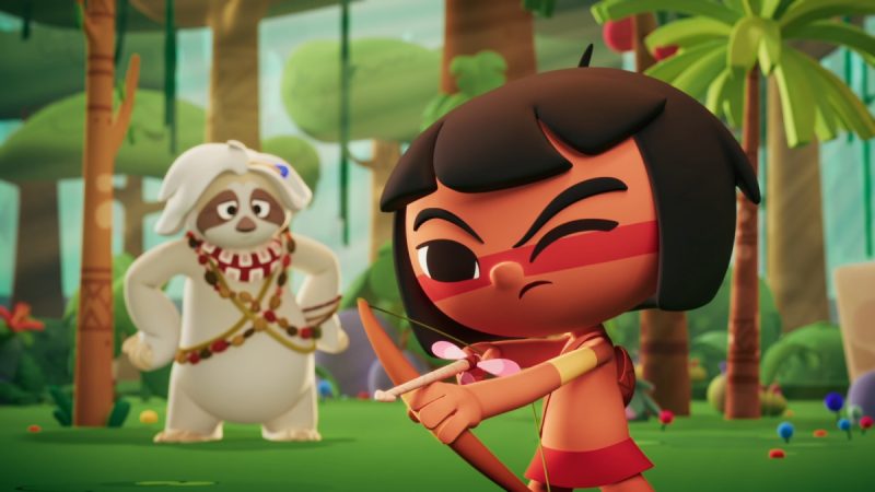 Animação colorida mostra uma menina de cabelos curtos e pretos, pele morena e pintura vermelha no rosto mirando com um arco e flecha de ponta rosa em formato de coração. Ao fundo, em uma floresta tropical, um personagem branco peludo, com adereços de colares e faixa na cabeça, observa com expressão curiosa.