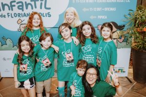 grupo de crianças com camisetas verdes posa alegre.