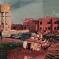 Fotografia panorâmica de um bairro de casas avermelhadas junto a uma área industrial e montanhosa.