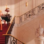 Animação mostra duas personagens sobre uma escadaria vermelha, diante de um piano em um salão elegante.