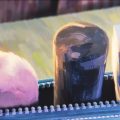 Animação em stop motion mostra três formas arredondadas pintadas em tons de rosa, preto e azul, alinhadas sobre uma estrutura.