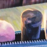 Animação em stop motion mostra três formas arredondadas pintadas em tons de rosa, preto e azul, alinhadas sobre uma estrutura.