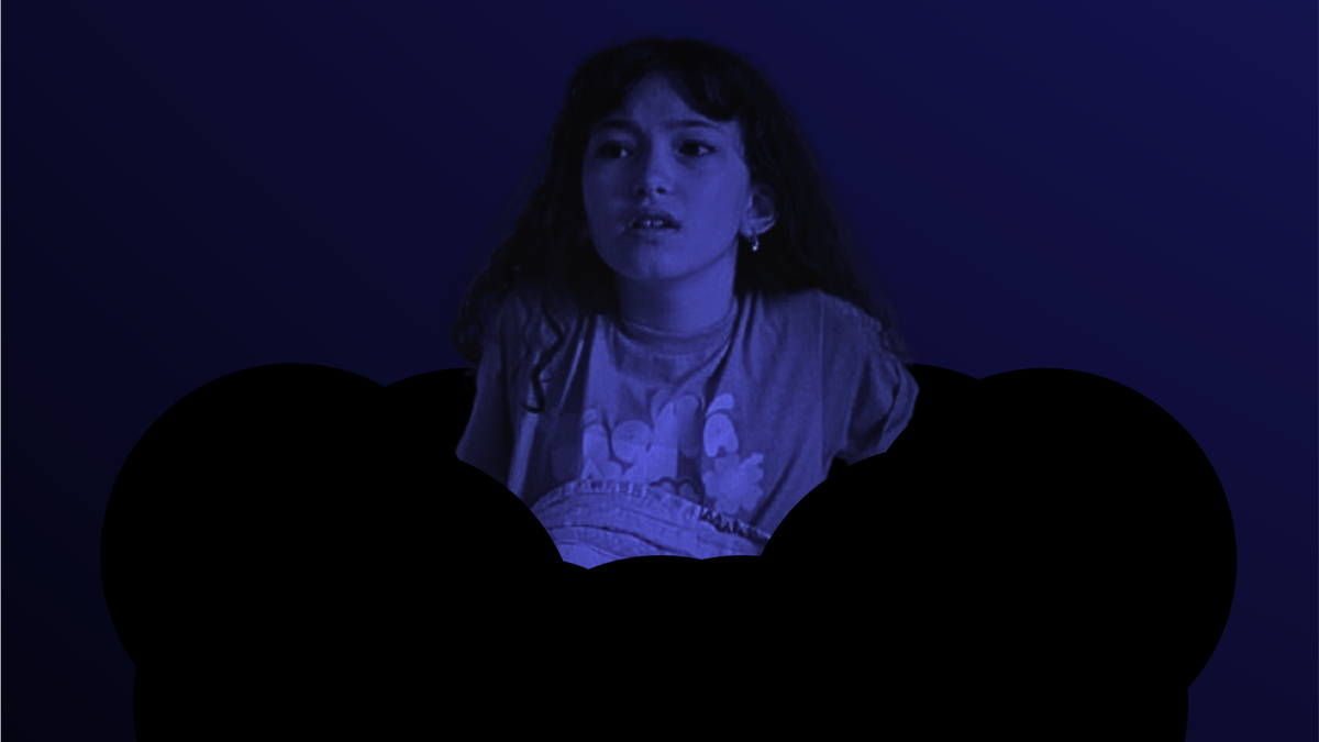 Fotografia em tons azulados de menina assustada entre silhuetas negras, olhando para o alto em ambiente escuro.